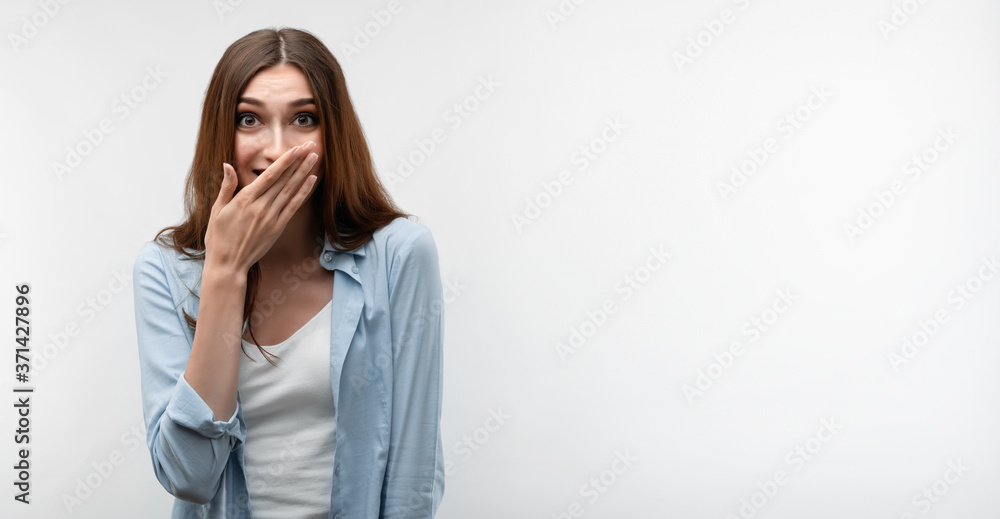 Charismatic girl with long chestnut hair covers her mouth with her hand Charismatic girl with long chestnut hair covers her mouth with her hand