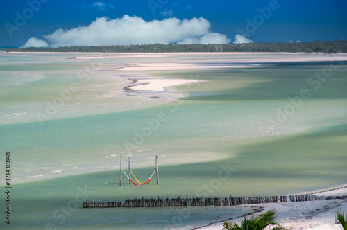 Panoramic aerial view of a tropical beach at low tide low tide, hammocks by the sea and white sand dunes in Holbox Island, Mexico. In the background the blue sky and white clouds