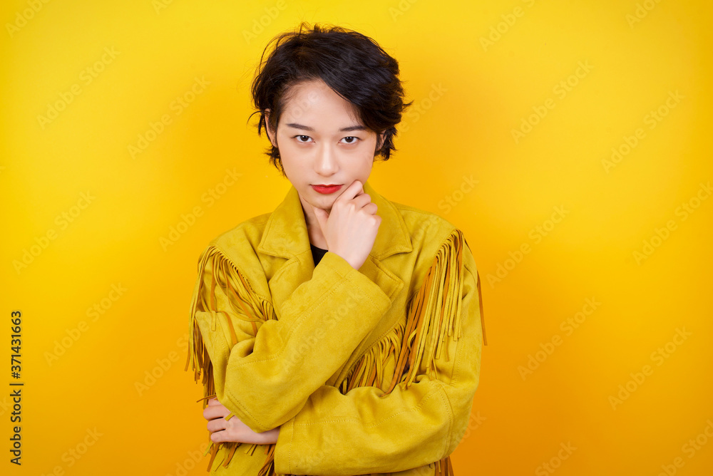 Portrait of thoughtful smiling girl keeps hand under chin, looks directly at camera, listens something with interest, dressed casually, poses against gray wall. Youth concept. Portrait of thoughtful smiling girl keeps hand under chin, looks directly at camera, listens something with interest, dressed casually, poses against gray wall. Youth concept.