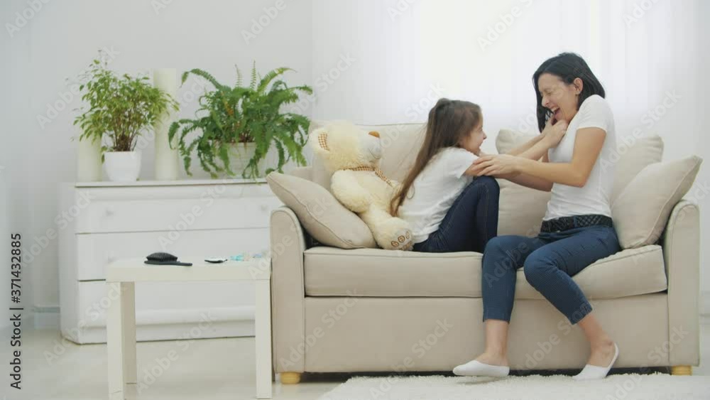 4k video of mother and daughter playing on sofa at home. 4k video of mother and daughter playing on sofa at home.