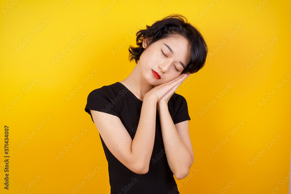 Relax and sleep time. Tired beautiful dark haired girl with closed eyes leaning on palms as pillow pretending sleeping being exhausted seeing dreams standing against gray background. Sleeping gesture. Relax and sleep time. Tired beautiful dark haired girl with closed eyes leaning on palms as pillow pretending sleeping being exhausted seeing dreams standing against gray background. Sleeping gesture.