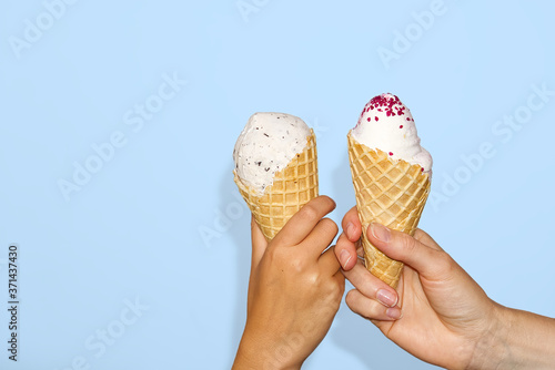 mother and daughter Hands holds ice cream corn with milk ice cream. isolated on a light blue background.