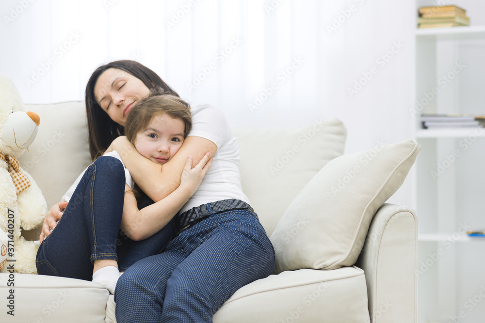 Photo of mother and daughter on white sofa.