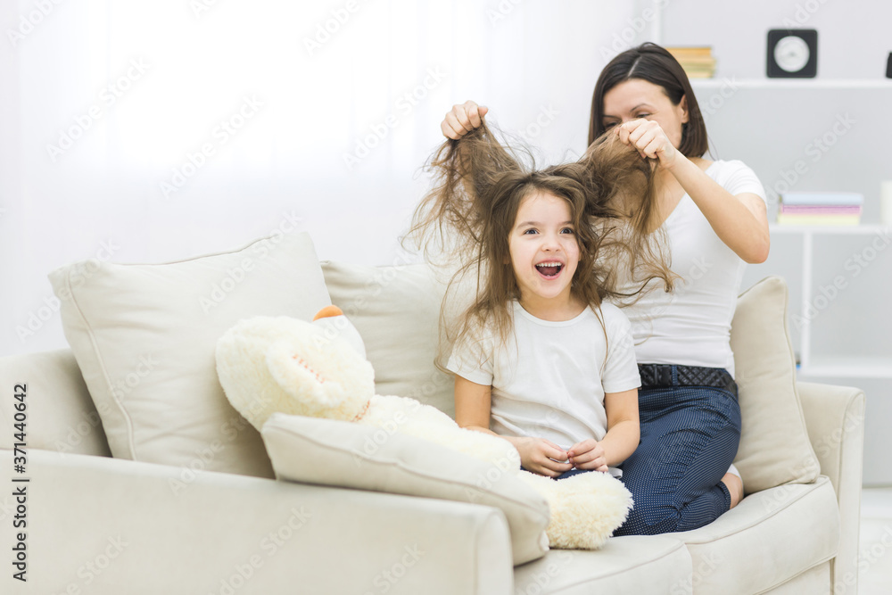 Cute little daughter and her beautiful young mother are playing.