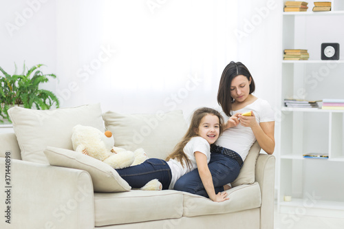 Photo of young mother and her daughter using smartphone.