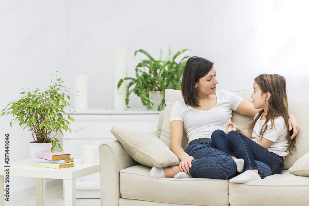 Photo of beautiful mother hugging with her cute little daughter and look each other in living room. Photo of beautiful mother hugging with her cute little daughter and look each other in living room.