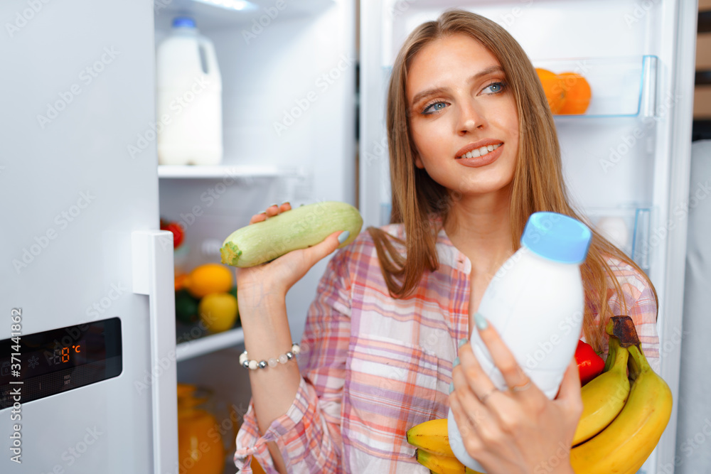 Portrait of a young blonde woman taking food from her fridge Portrait of a young blonde woman taking food from her fridge
