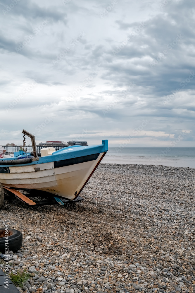 A traditional crab fishing boat on the shingle at Cromer beach after a morning at sea setting crab pots. This is portrait orientation with copy space