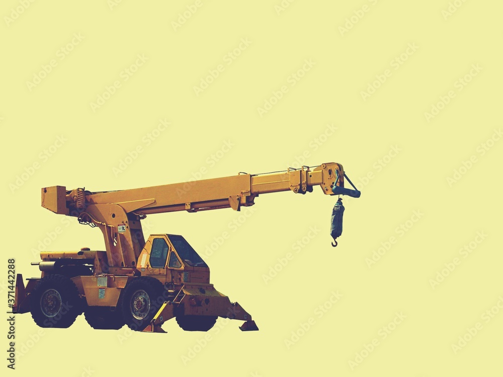 Construction backhoe with a pale yellow background