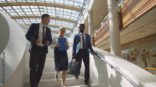 Canvastavla Multiethnic business people walking downstairs discussing presentation
