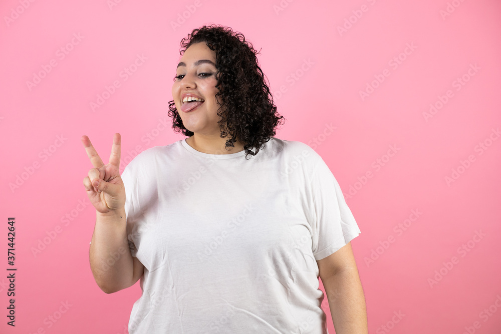 Young brunette woman over isolated pink background smiling with happy face doing victory sign. Number two. Young brunette woman over isolated pink background smiling with happy face doing victory sign. Number two.