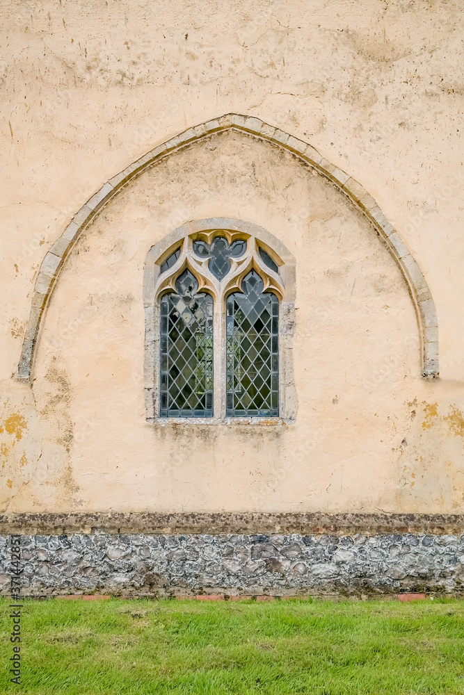 Ornate patterned window under a concrete arch in the porch of a Norfolk church