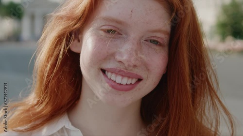 Cute carefree ginger girl with beautiful hair and freckles showing beautiful happy smile at camera enjoying summertime staying outside. Portraits. Females. photo