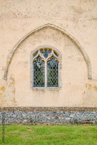 Ornate patterned window under a concrete arch in the porch of a Norfolk church © yackers1