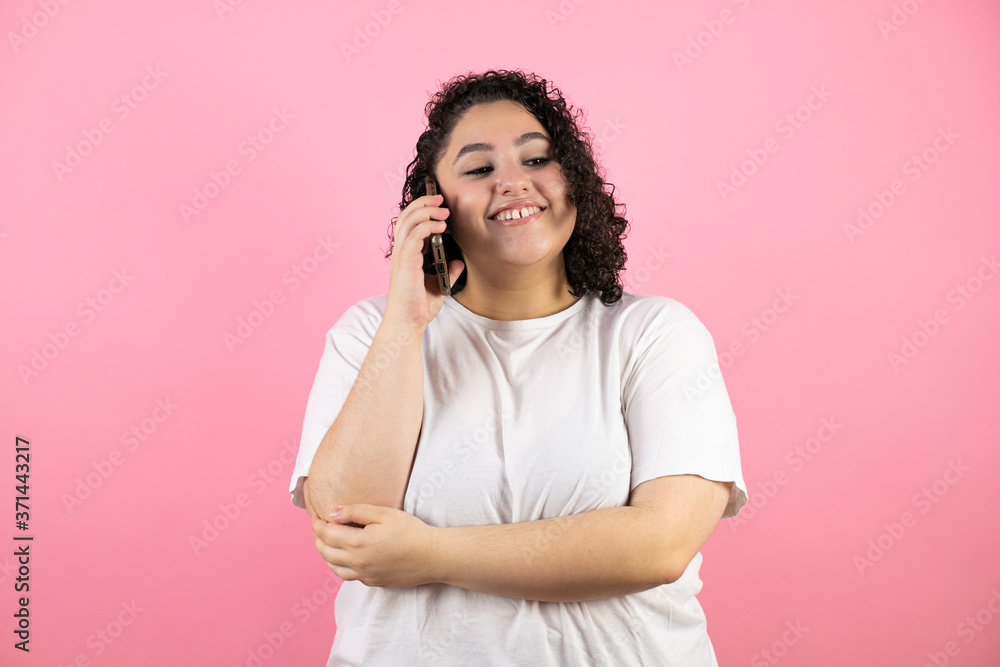 Young beautiful woman talking on the phone, smiling on pink background. Young beautiful woman talking on the phone, smiling on pink background.