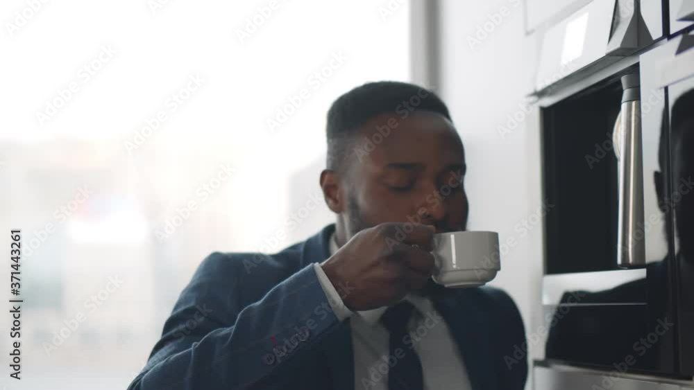 Close up of african businessman making coffee in coffee machine in office cafeteria Close up of african businessman making coffee in coffee machine in office cafeteria