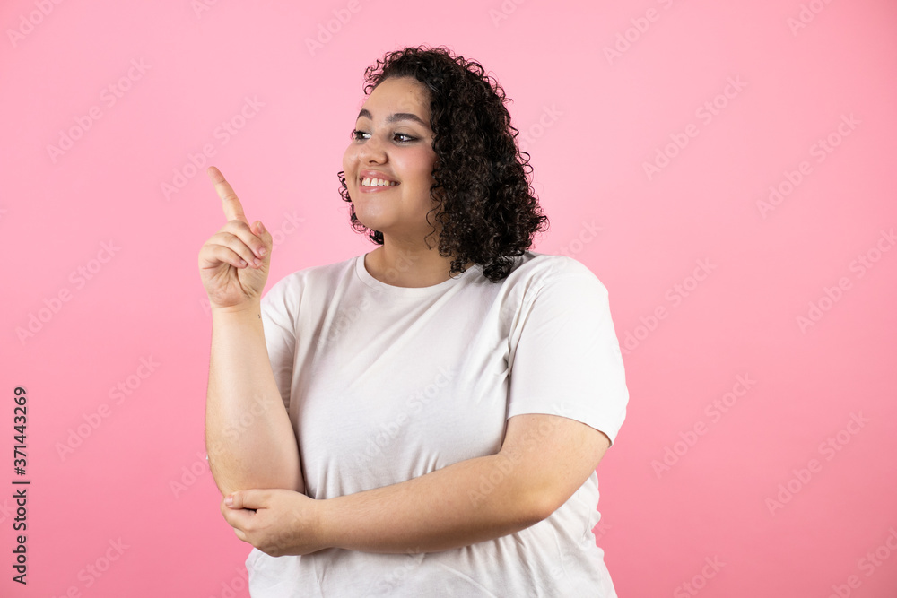 Young beautiful woman standing over isolated pink background smiling happy pointing with hand and finger to the side Young beautiful woman standing over isolated pink background smiling happy pointing with hand and finger to the side