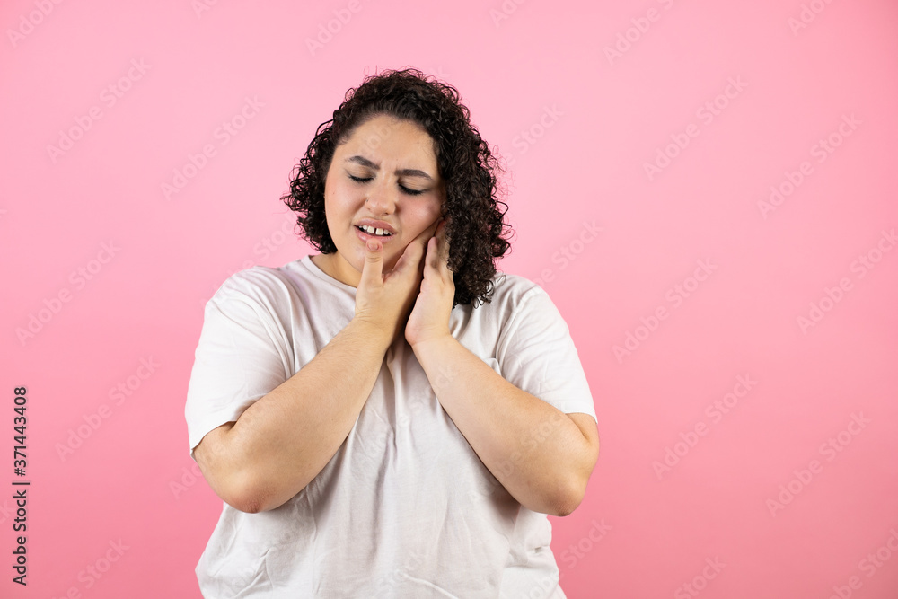 Beautiful woman wearing casual white t-shirt over isolated pink background touching mouth with hand with painful expression because of toothache or dental illness on teeth Beautiful woman wearing casual white t-shirt over isolated pink background touching mouth with hand with painful expression because of toothache or dental illness on teeth