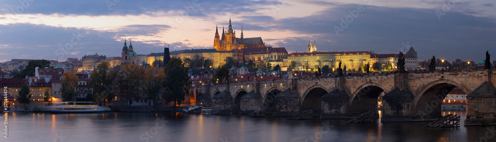 Prague - The panorama of Charles Bridge, Castle and Cathedral from promenade over the  Vltava river at dusk.