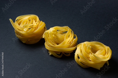 nests of pasta on a black background. Italian pasta. The pasta nests are in a row. European cuisine