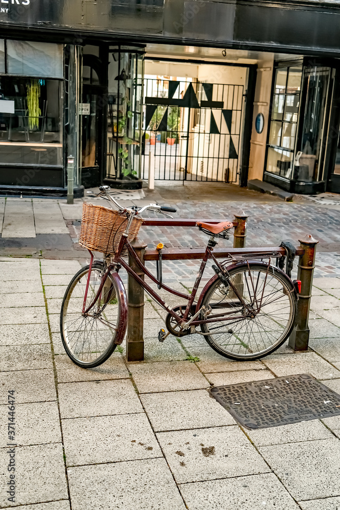 A retro style bicycle with a basket on the handle bars locked to an outdoor bike rack in the city centre of Norwich, Norfolk