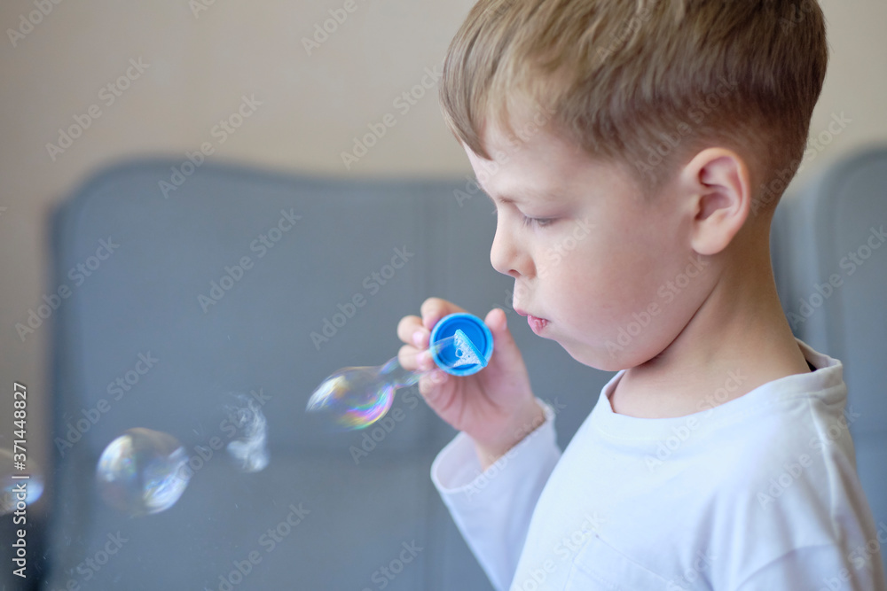 boy blowing soap bubbles. The boy makes soap bubbles. Blowing on bubbles. Children's games at home. Home fun