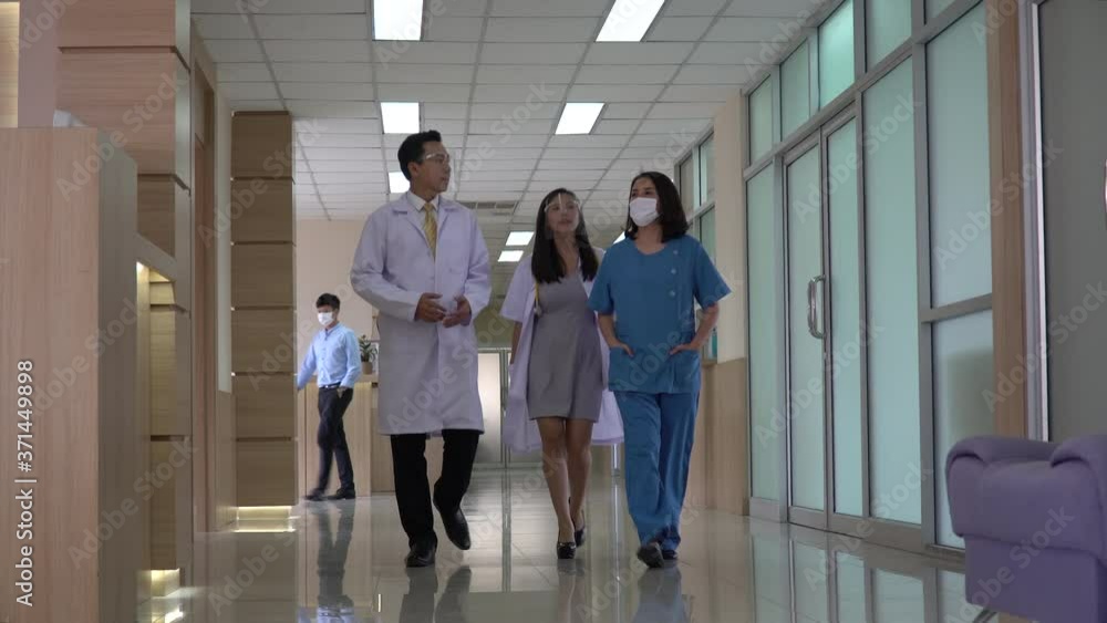 group of asian doctor and patient wearing medical mask and face shield working and walking through hospital hallway protect coronavirus outbreak or Covid-19 pandemic group of asian doctor and patient wearing medical mask and face shield working and walking through hospital hallway protect coronavirus outbreak or Covid-19 pandemic