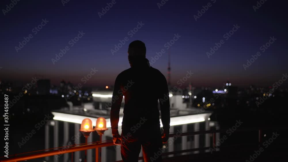 Strong man in disguise looking around on night roof, hero ready to fight crime Strong man in disguise looking around on night roof, hero ready to fight crime