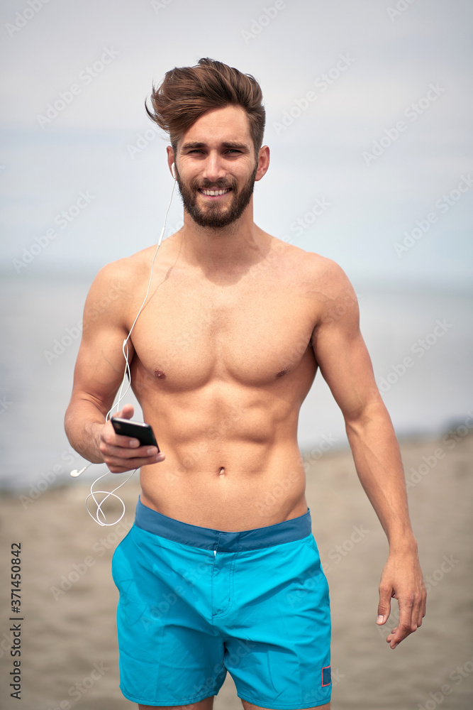 Obraz premium Attractive man walking on the beach; Hot guy concept