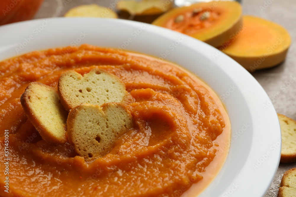 Plate of pumpkin puree with croutons on gray background, close up Plate of pumpkin puree with croutons on gray background, close up