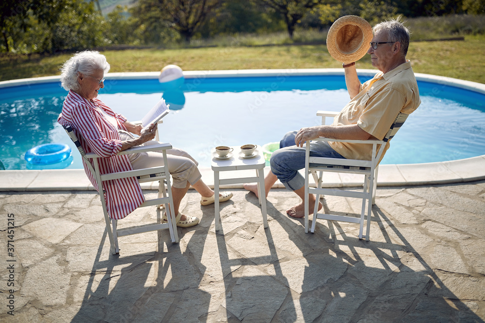 Senior man and woman enjoy on summer holiday near swimming pool.