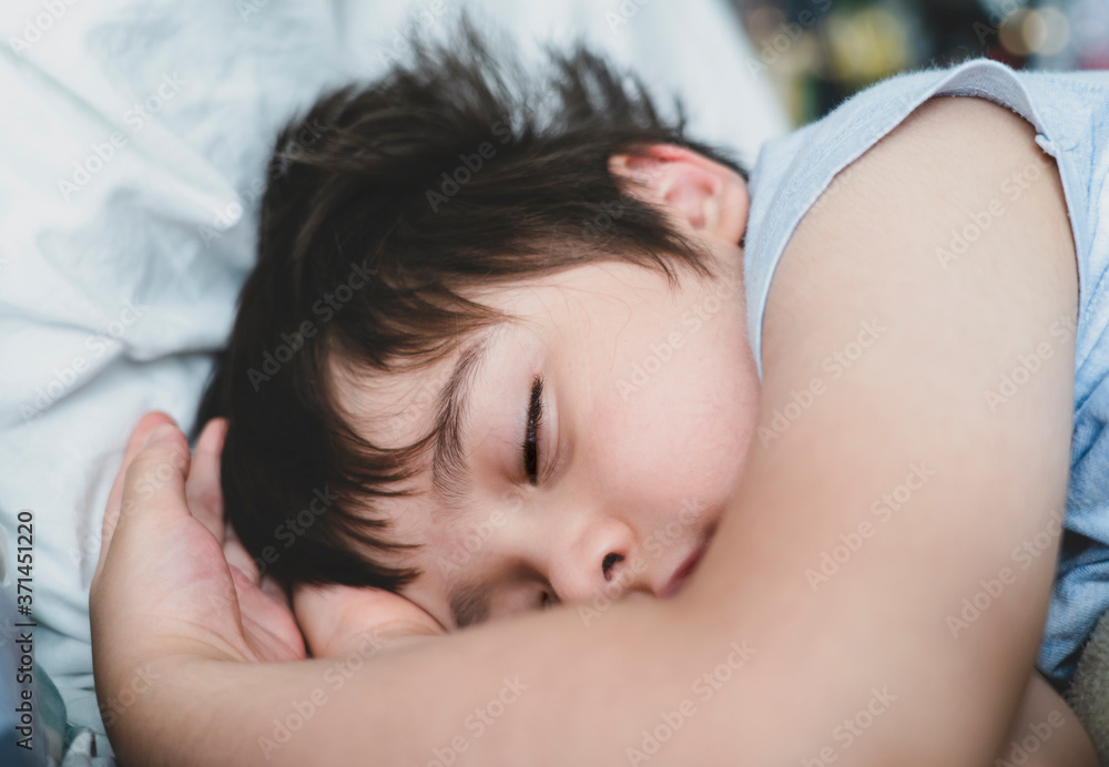 Cropped shot Child boy sleep with his eyes half open on his bed, Close up Young Kid sleeping with open eyed while taking a nap, Sleep problems in young children concept or REM sleep Cropped shot Child boy sleep with his eyes half open on his bed, Close up Young Kid sleeping with open eyed while taking a nap, Sleep problems in young children concept or REM sleep