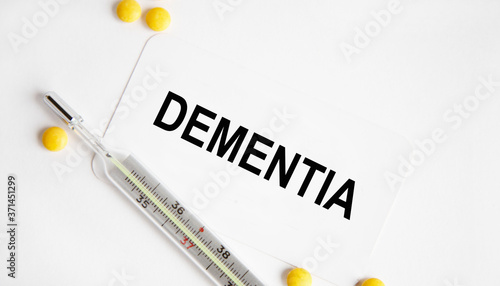 The inscription on the BUSINESS card DEMENTIA, next to lie yellow tablets and a thermometer.