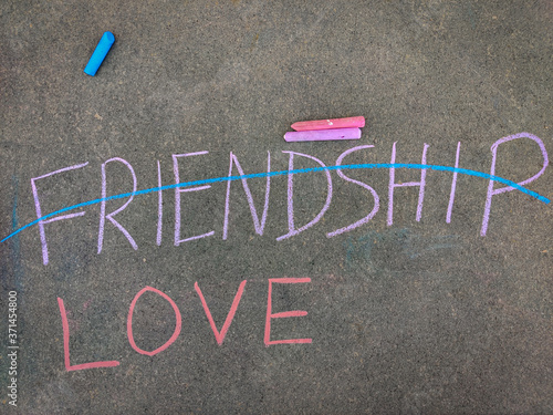 The inscription text on the grey board, LOVE and crossed out FRIENDSHIP inscription.Using color chalk pieces