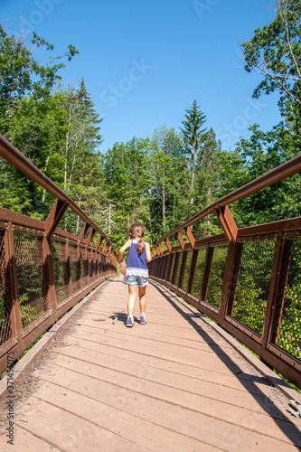 Little girl walking over a foot bridge in the woods