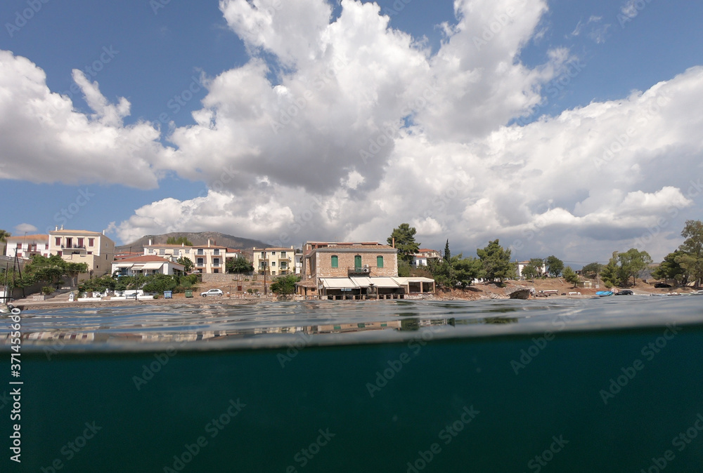Split underwater photo from small port of Hirolakas depicting neoclassic architecture in historic and picturesque seaside village of Galaxidi, Fokida, Greece