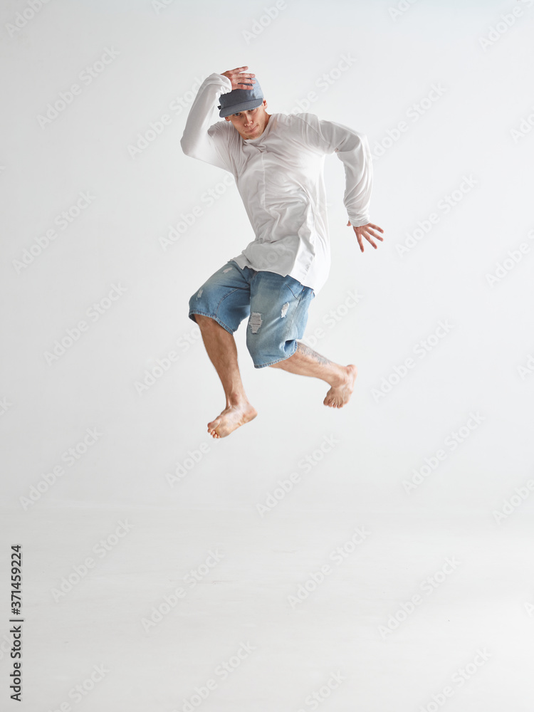 Young guy breakdancer jumps dancing hip-hop isolated on white background. Dance school poster. Break dance lessons
