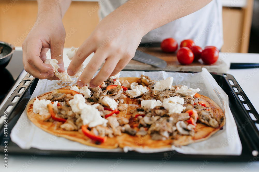 Home made pizza. Person putting on mozzarella on dough with ketchup,chicken and mushrooms on modern white kitchen. Process of making pizza, ingredients close up. Home cooking concept