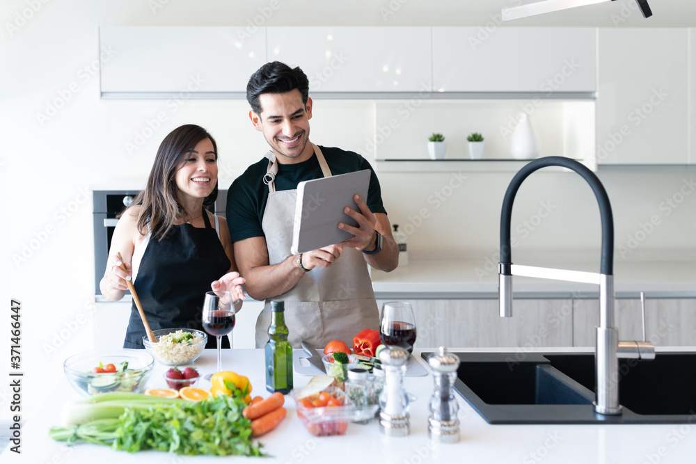 Young Couple Preparing Food Through Online Recipe
