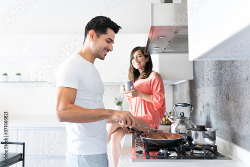 Handsome Man Cooking Food While Woman Having Coffee
