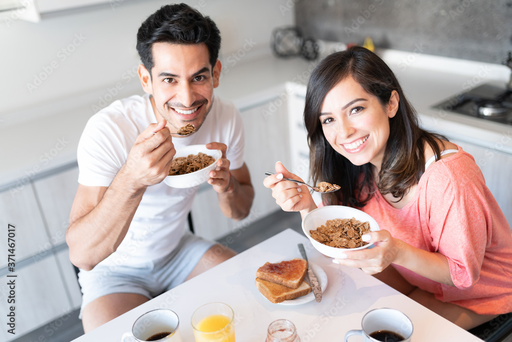 Hispanic Couple Eating Breakfast In Kitchen