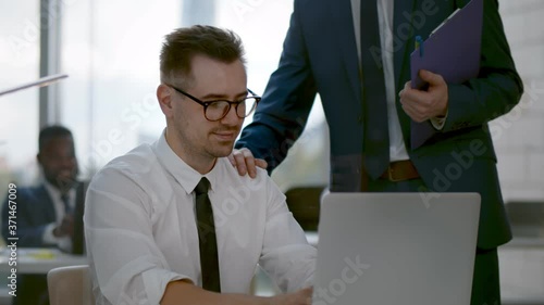 Team leader encourage and pat on shoulder expressing positive successful to young man employee