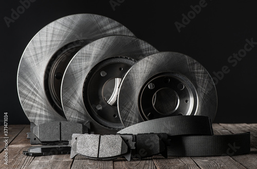 Row of brake discs and friction pads on rustic wooden table photo