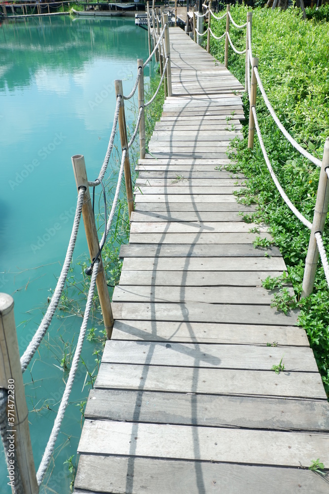 Fototapeta premium Brown wooden bridge beside the pond.