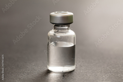 Medical vial for injection on gray background, transparent glass bottle, drug medicine vaccine dose.