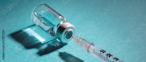 Foto Vaccine vial dose and syringe against blue background
