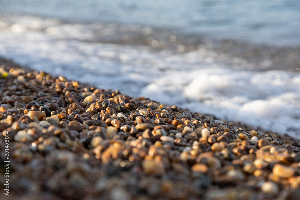 the rocky shore of the lake in the afternoon sun with the waves the rocky shore of the lake in the afternoon sun with the waves