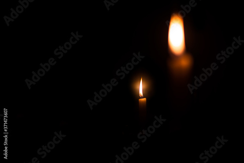 white wax candle burning in the dark isolated with copyspace