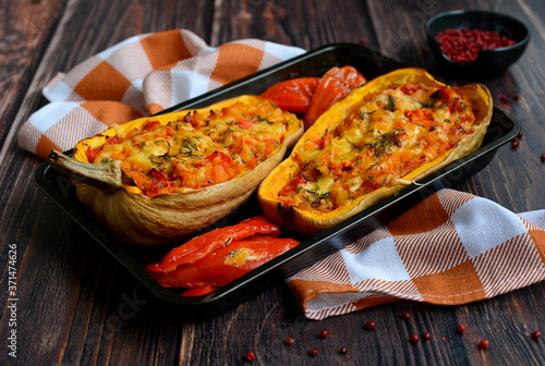 Dark baking tray with baked pumpkin and halves of pepper and a checkered towel