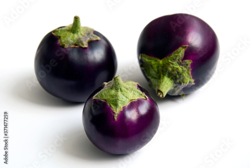 Three round purple eggplants on a white background.